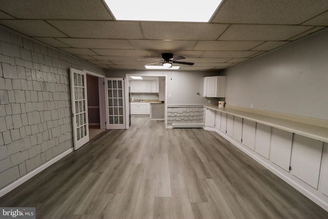 interior space featuring ceiling fan, light hardwood / wood-style flooring, a drop ceiling, and french doors