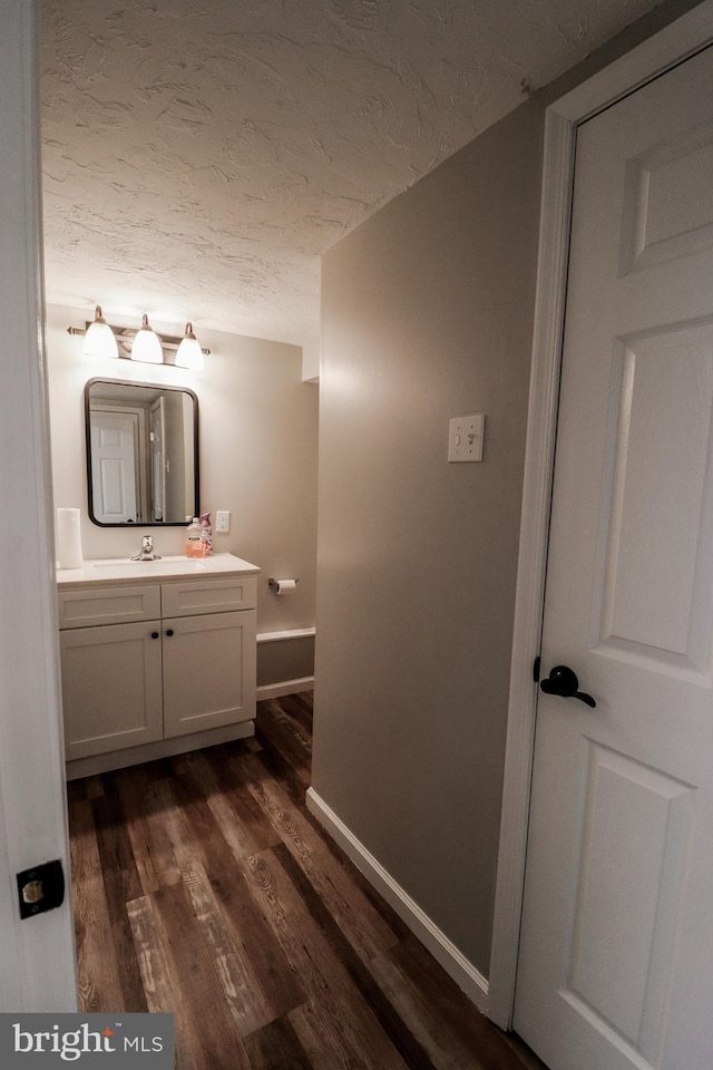 bathroom with wood-type flooring, vanity, and a textured ceiling