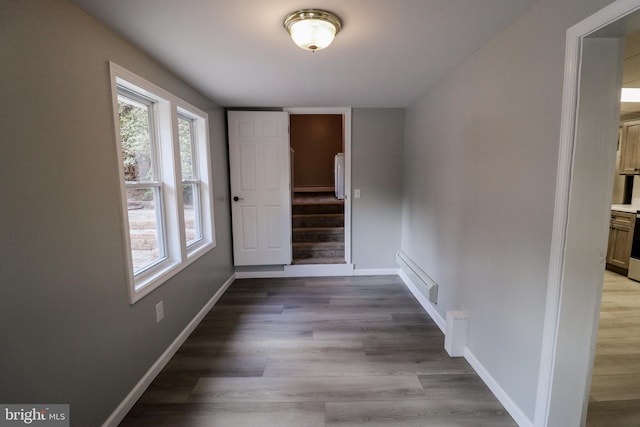 hall with light hardwood / wood-style floors and a baseboard heating unit