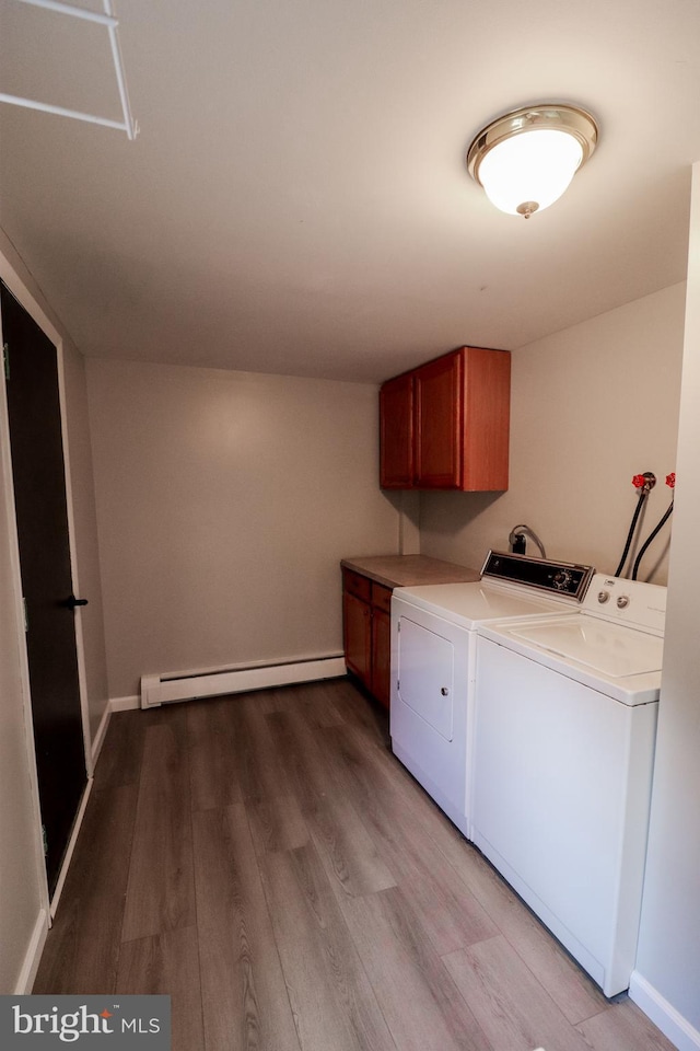 clothes washing area featuring independent washer and dryer, cabinets, light wood-type flooring, and a baseboard heating unit