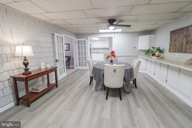 6381 Glatfelters Station Rd, Seven Valleys, PA 17360 - dining space featuring french doors, a ceiling fan, light wood-style floors, a paneled ceiling, and wainscoting