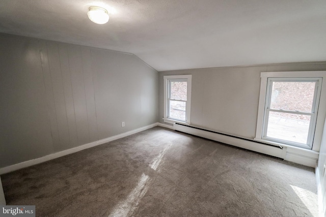 empty room featuring a baseboard radiator, lofted ceiling, and dark carpet