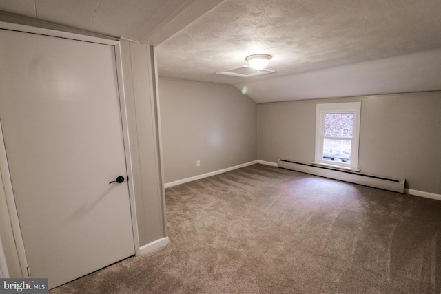 carpeted empty room featuring a textured ceiling, baseboard heating, and vaulted ceiling