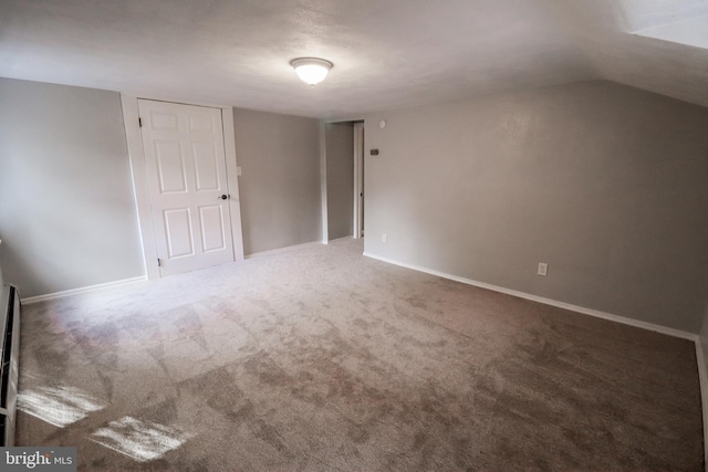 carpeted spare room with vaulted ceiling