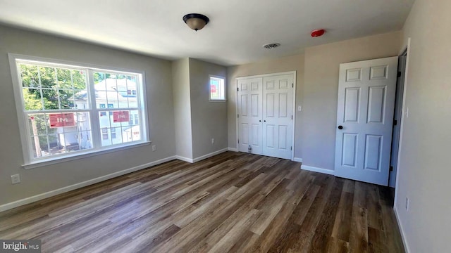 unfurnished bedroom featuring dark hardwood / wood-style floors and a closet