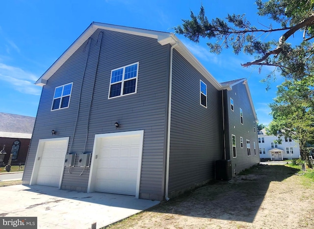 rear view of property featuring a garage and central AC