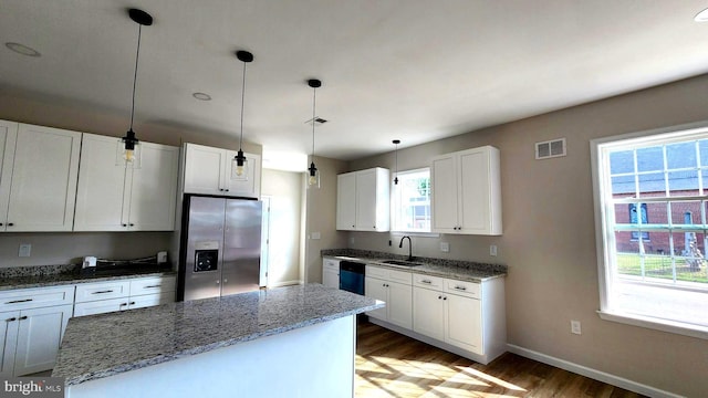 kitchen featuring white cabinetry, stainless steel fridge with ice dispenser, a healthy amount of sunlight, and decorative light fixtures