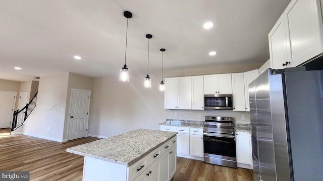 kitchen featuring appliances with stainless steel finishes, a center island, white cabinetry, and hardwood / wood-style floors