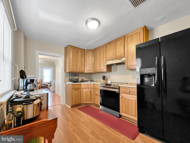 kitchen with black fridge with ice dispenser, light brown cabinets, light hardwood / wood-style floors, and stainless steel range with electric stovetop