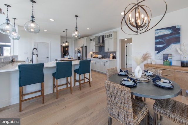 dining room with a chandelier, sink, and light hardwood / wood-style flooring