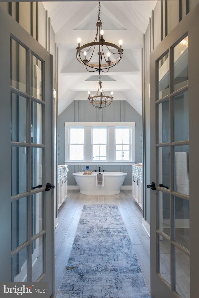 bathroom featuring hardwood / wood-style floors, a washtub, lofted ceiling, and a chandelier