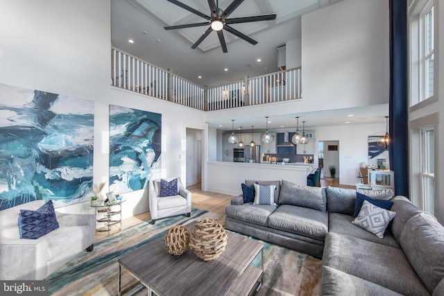 living room with a high ceiling, hardwood / wood-style flooring, and ceiling fan