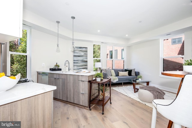 kitchen with plenty of natural light, light hardwood / wood-style floors, decorative light fixtures, and sink