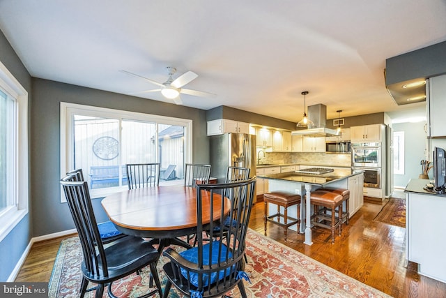 dining area featuring ceiling fan, dark wood-type flooring, and sink