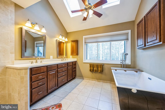 bathroom featuring tile patterned floors, a bathtub, vanity, lofted ceiling with skylight, and ceiling fan