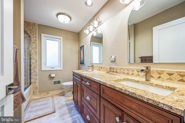 full bathroom featuring shower / bath combination with glass door, vanity, toilet, and a wealth of natural light