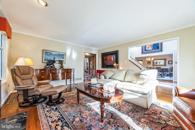 living room with crown molding, a chandelier, and hardwood / wood-style flooring