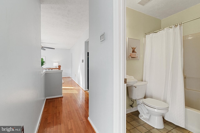 bathroom with hardwood / wood-style floors, ceiling fan, shower / bath combo with shower curtain, and a textured ceiling