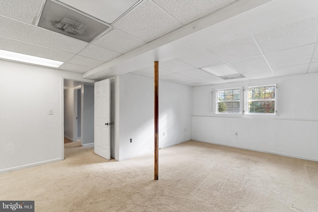 basement featuring a paneled ceiling and light colored carpet