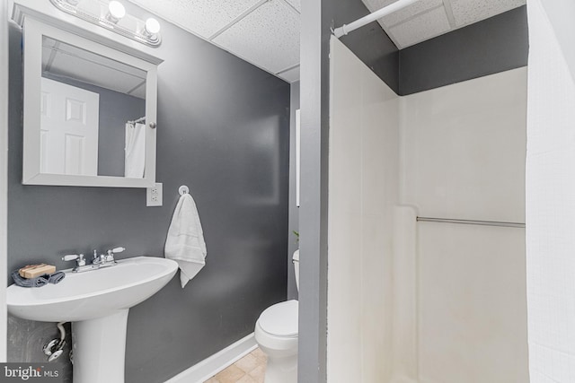 bathroom featuring sink, walk in shower, tile patterned floors, toilet, and a paneled ceiling