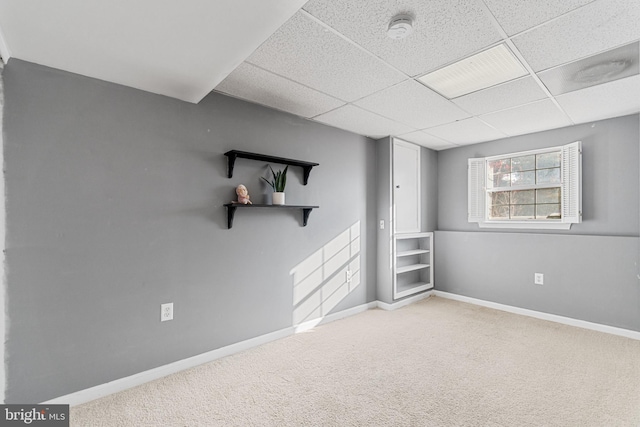 empty room with a paneled ceiling and light carpet