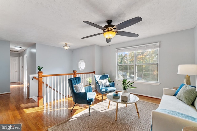 sitting room with wood-type flooring, a textured ceiling, and ceiling fan