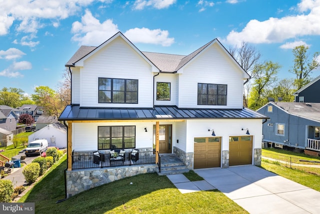 modern inspired farmhouse featuring covered porch, a garage, and a front yard