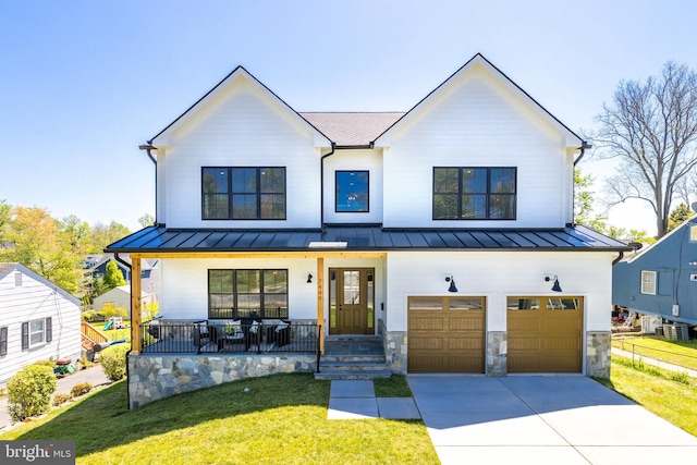 modern farmhouse with a front lawn, covered porch, and a garage