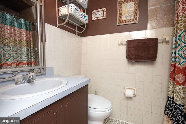 bathroom with vanity, toilet, and tile walls