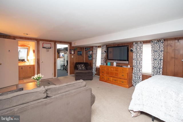 bedroom featuring ensuite bath, wooden walls, and light carpet