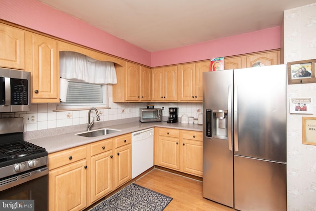 kitchen with sink, light brown cabinets, backsplash, light hardwood / wood-style floors, and appliances with stainless steel finishes