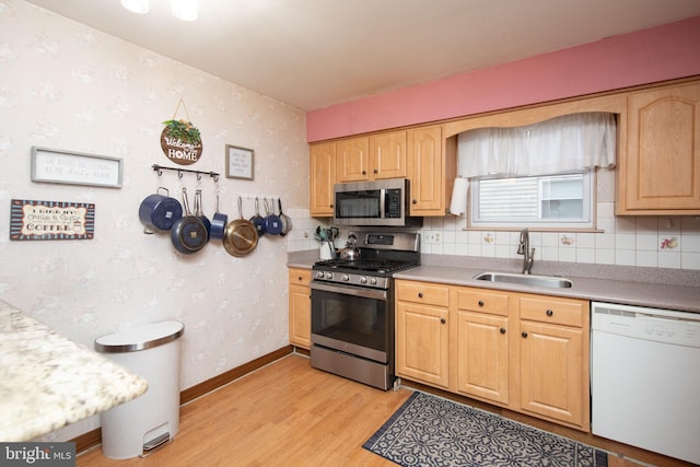 kitchen featuring sink, tasteful backsplash, light hardwood / wood-style flooring, light brown cabinetry, and appliances with stainless steel finishes