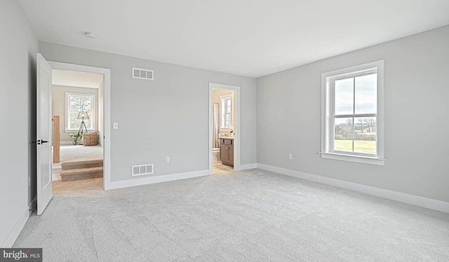 unfurnished bedroom with connected bathroom and light carpet