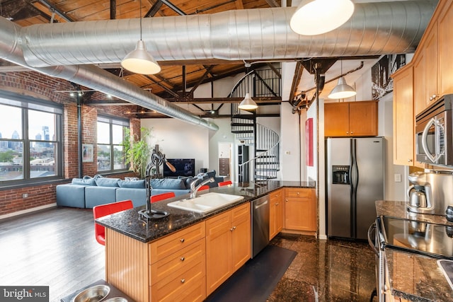 kitchen with appliances with stainless steel finishes, brick wall, sink, decorative light fixtures, and dark hardwood / wood-style floors