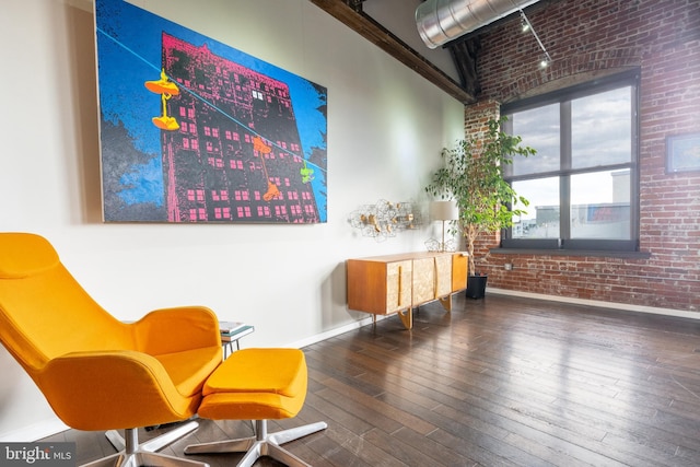 living area featuring wood-type flooring and brick wall