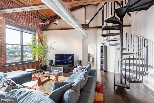 living room featuring dark wood-type flooring, beamed ceiling, brick wall, and a high ceiling