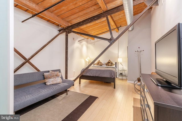 bedroom featuring beamed ceiling, a high ceiling, light hardwood / wood-style flooring, and wood ceiling