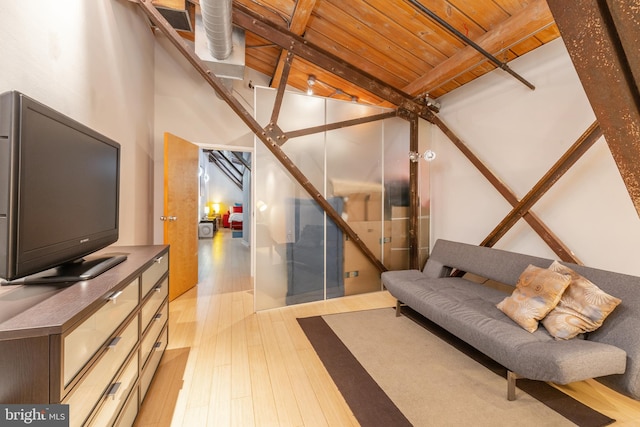 living room featuring beamed ceiling, light hardwood / wood-style floors, wooden ceiling, and a high ceiling