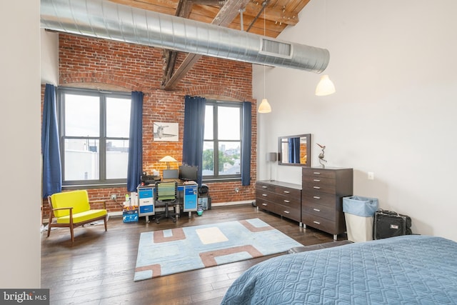 bedroom with beamed ceiling, dark hardwood / wood-style flooring, a high ceiling, and brick wall