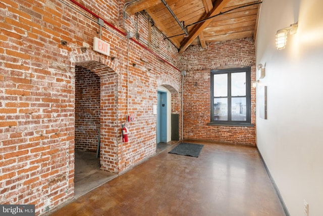 corridor featuring concrete flooring, beamed ceiling, wood ceiling, and a high ceiling