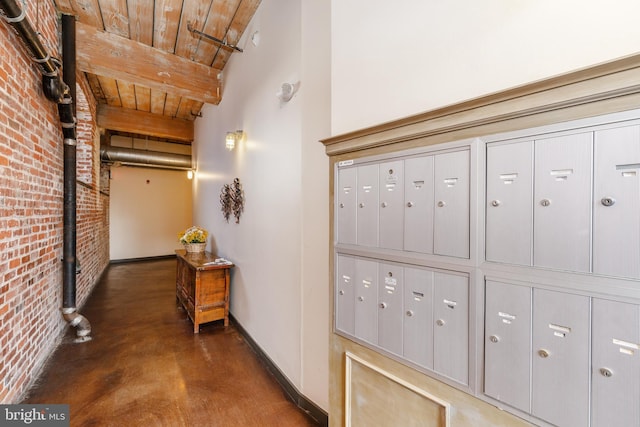 hallway with a mail area, wooden ceiling, and brick wall