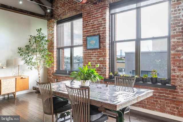 dining room with a healthy amount of sunlight, dark wood-type flooring, and brick wall