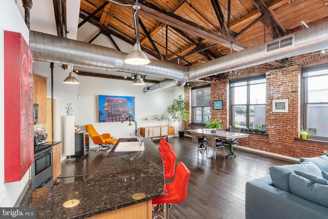 kitchen featuring pendant lighting, high vaulted ceiling, dark hardwood / wood-style floors, wood ceiling, and brick wall