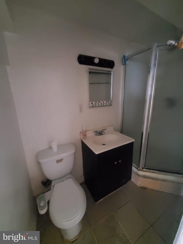 bathroom with tile patterned flooring, vanity, toilet, and a shower with door