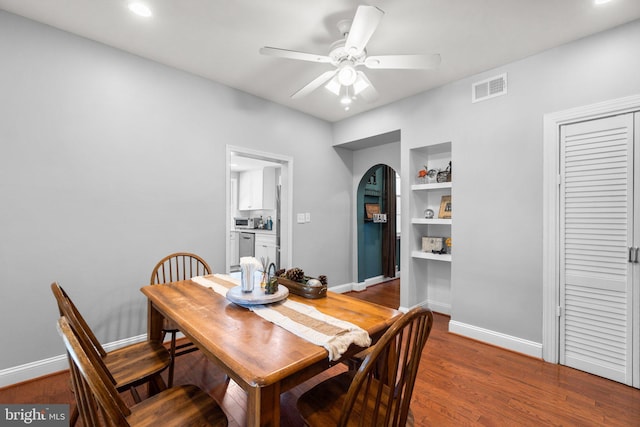 dining area featuring built in shelves, dark wood-type flooring, and ceiling fan