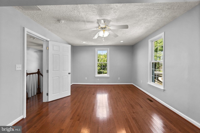 unfurnished bedroom featuring ceiling fan, a spacious closet, a textured ceiling, and dark hardwood / wood-style flooring