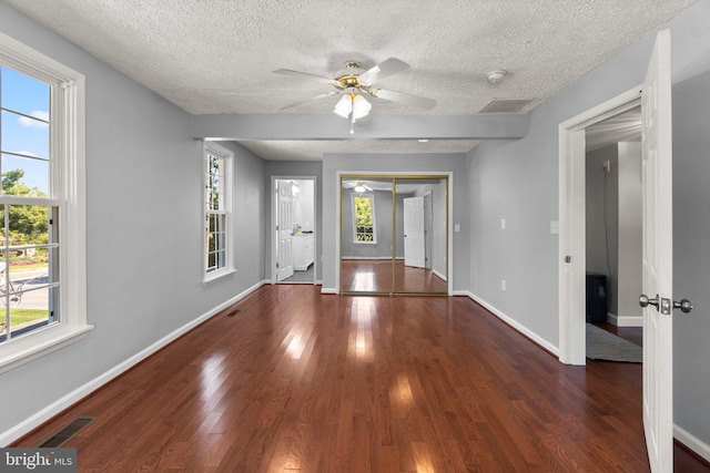 interior space with ceiling fan, plenty of natural light, a textured ceiling, and dark hardwood / wood-style flooring