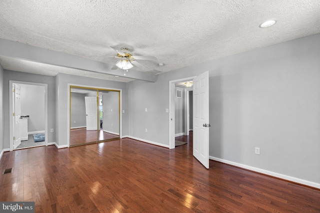 empty room with ceiling fan, dark wood-type flooring, and a textured ceiling