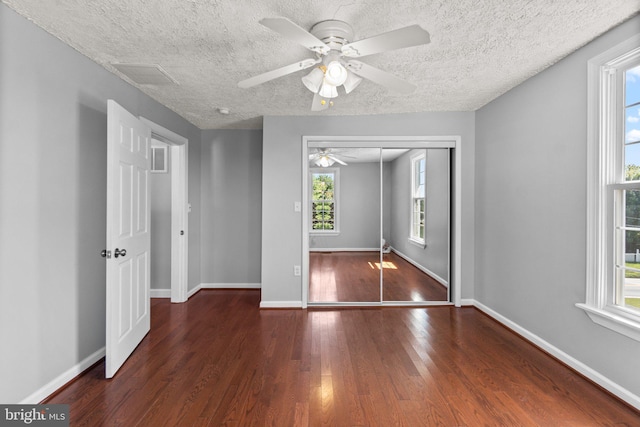 unfurnished bedroom with ceiling fan, dark wood-type flooring, a textured ceiling, and a closet