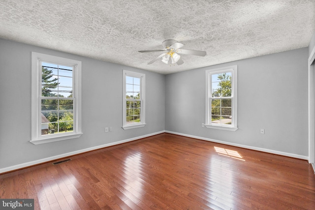 spare room featuring hardwood / wood-style flooring, ceiling fan, a textured ceiling, and a wealth of natural light